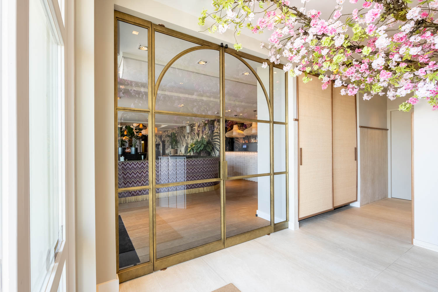 Luxe messing stalen schuifdeuren met glas en elegante boogdetails, als stijlvolle entree naar een chique interieur.